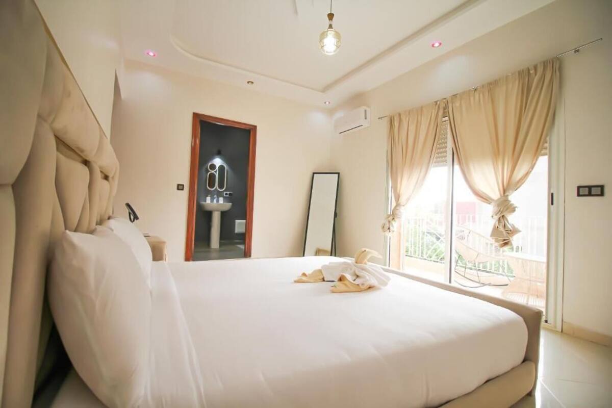A hotel room with a large bed, a bathroom mirror, and a view of the outside balcony.