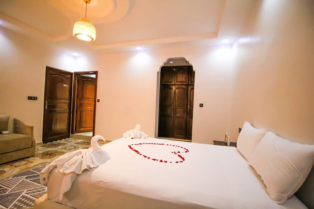 A hotel room with a bed, a sofa, and two doors.