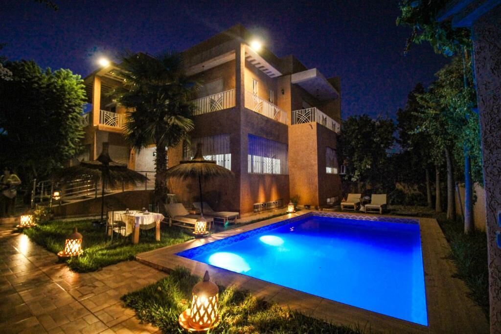 A two-story building with a swimming pool, outdoor seating, and decorative lighting.