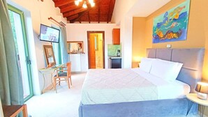 Ein Schlafzimmer mit einem großen Bett, einem Schreibtisch, einem Stuhl, einem Fernseher und einem Bild an der Wand.