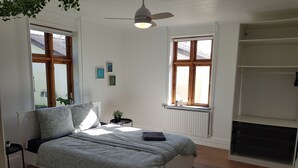A bedroom with a bed, a ceiling fan, a radiator, and a window. - Stay Billund – lovely holiday apartment just 5 minutes from Legoland (Vandel)