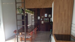 A dining area with a wooden table, red chairs, a ladder, and a kitchen area with a wooden counter. - Stay Billund – lovely holiday apartment just 5 minutes from Legoland (Vandel)