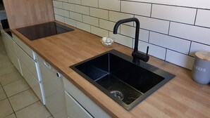 A kitchen with a black sink, wooden countertop, and white tiled backsplash. - Stay Billund – lovely holiday apartment just 5 minutes from Legoland (Vandel)