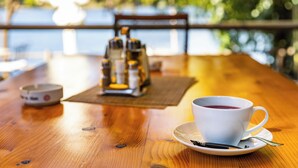 A wooden table with a white cup of tea, a teapot, and a sugar bowl. - HOTEL DIESEL (Bucharest)
