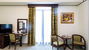 A hotel room with a desk, two chairs, a television, and a painting on the wall. - HOTEL DIESEL (Bucharest)