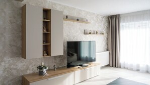 Una sala de estar moderna con un televisor de pantalla plana, estanterías empotradas, un mueble bajo de madera y un radiador.