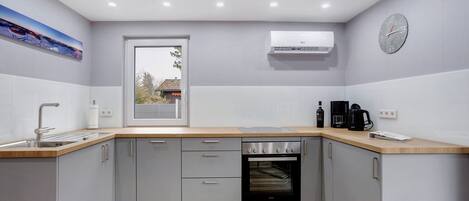 A modern kitchen with grey cabinets, a wooden countertop, an oven, and a window with a view.
