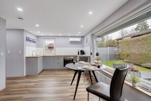 A modern kitchen with a dining area, a large window, and a view of the garden. - Holiday Home Adelon with Private Terrace, Wi-Fi, and Air Conditioning at Lake Möhnesee (Möhnesee)