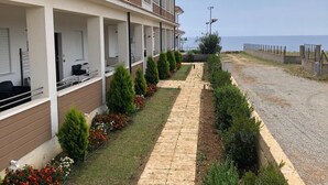 Un bâtiment moderne doté d’un espace extérieur couvert, d’un chemin pavé et d’une vue sur la mer.