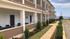 Un hôtel à plusieurs étages, doté de balcons, d’une promenade dallée et offrant une vue sur la mer.