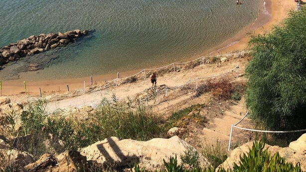 Une plage côtière avec une eau claire, des affleurements rocheux et un rivage sablonneux.