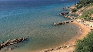 Una playa costera con agua cristalina, afloramientos rocosos y una orilla arenosa.