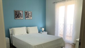 Une chambre à coucher avec un grand lit, deux oreillers blancs, une table de chevet avec une lampe et deux œuvres d’art murales.