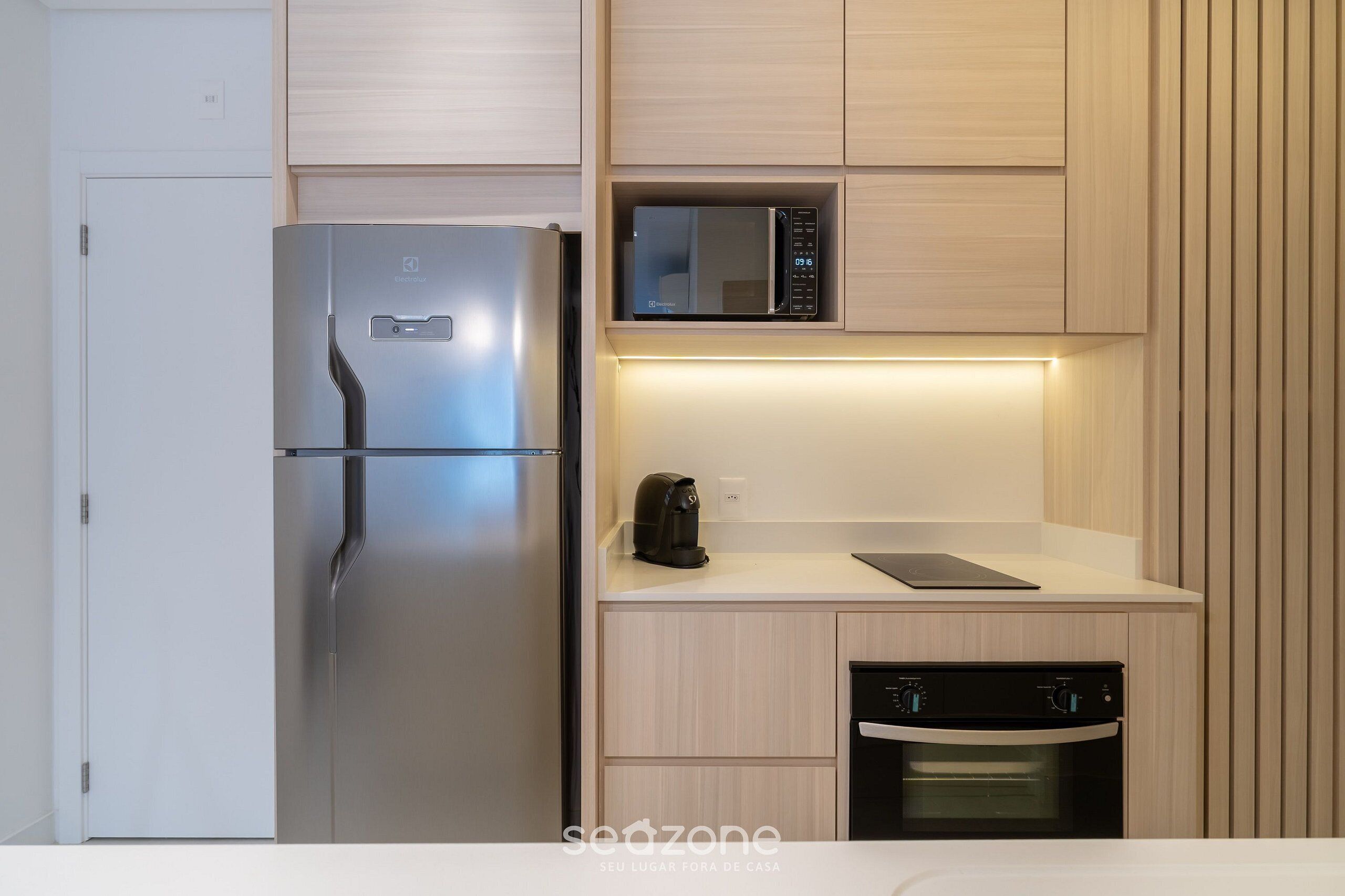 A modern kitchen with a stainless steel refrigerator, a microwave, a coffee maker, and a dishwasher.