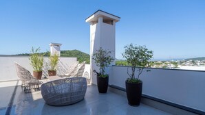 A rooftop terrace with potted plants, wicker furniture, and a clear view of the city and hills in the background. - Ap in a Condominium With gym in Jurere Vox0210 (Florianópolis)