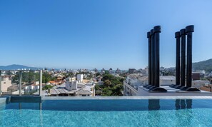 A rooftop infinity pool with a clear view of a cityscape and distant mountains. - Ap in a Condominium With gym in Jurere Vox0210 (Florianópolis)