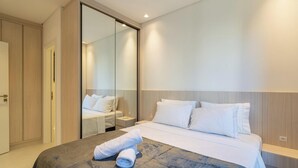 A modern hotel room with a large bed, a bedside table, a mirror, and a wardrobe. - Ap in a Condominium With gym in Jurere Vox0210 (Florianópolis)