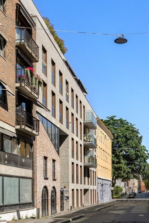 A multi-story building with a mix of brick and modern facade, featuring balconies with flower boxes and large windows. - Quiet Studio in Oslo Center Queen Bed & Rooftop (Oslo)