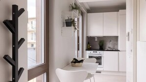 Une cuisine moderne avec des meubles blancs, un plan de travail noir et un coin repas comprenant une table et des chaises blanches.