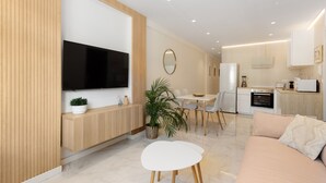 Una sala de estar moderna con televisor de pantalla plana, un comedor, una cocina y un sofá.