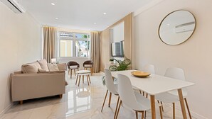 Una sala moderna con un sofá, mesa de comedor, sillas y un televisor.