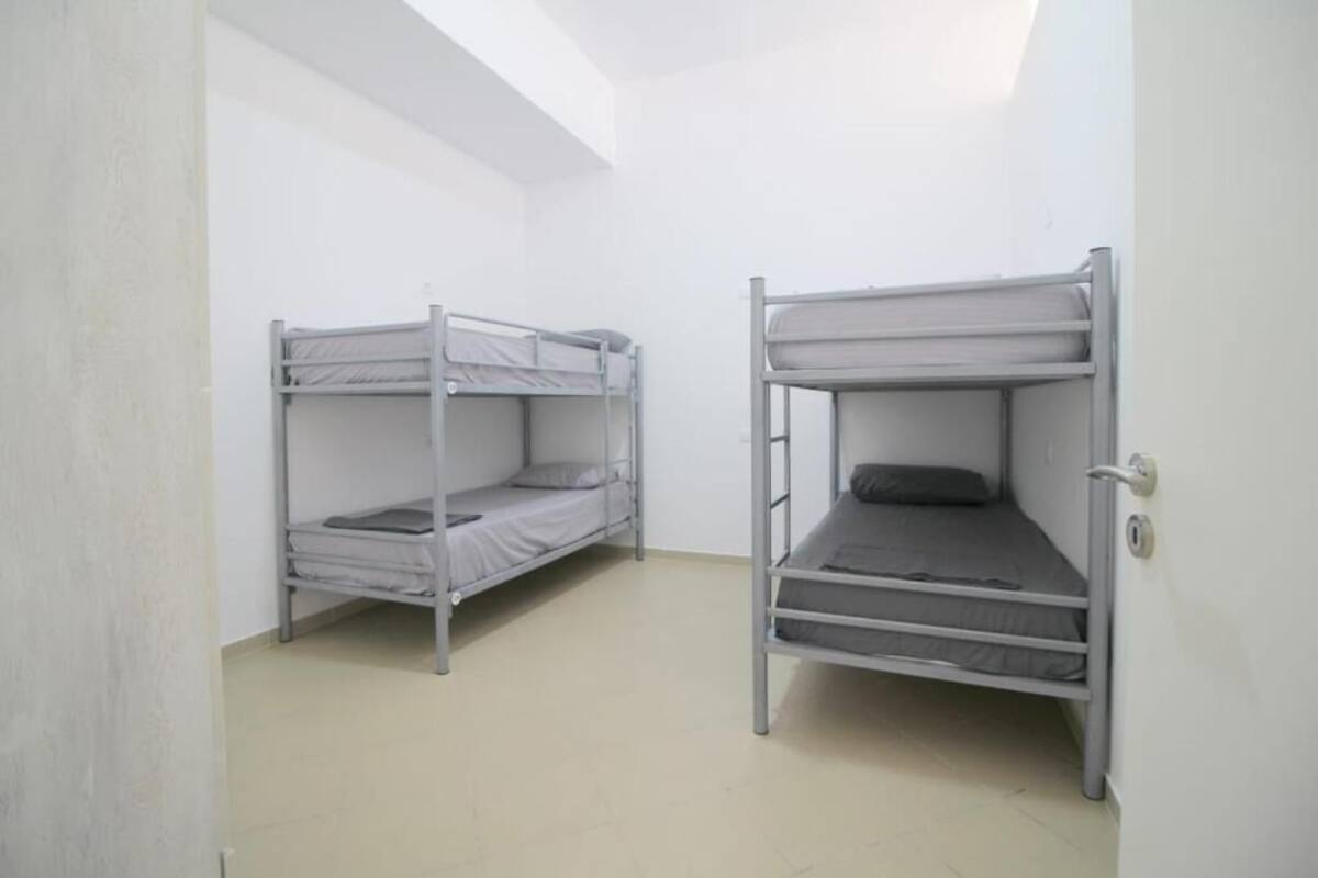 A room with two bunk beds, white walls, and a skylight.