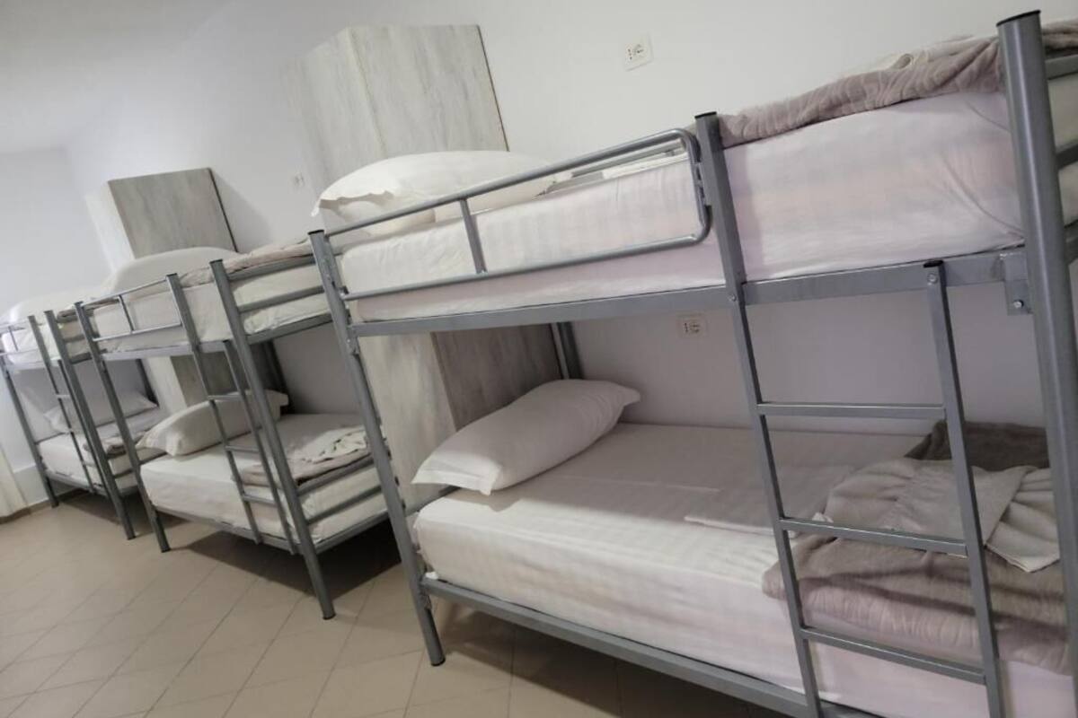 A dormitory room with bunk beds, a wardrobe, and a bedside table.