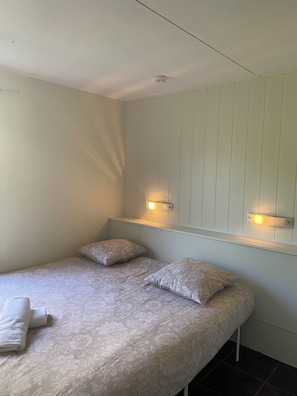 A single bed with floral bedding, two pillows, a wall-mounted shelf with lights, and a ceiling light fixture. - fasthotel troyes  (Barberey-Saint-Sulpice)
