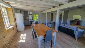 A rustic kitchen with a wooden table and chairs, a refrigerator, and a washing machine. - Charming cottage Les Prés (Saint-Cyprien)