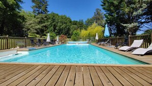 A wooden deck with a swimming pool, surrounded by trees and a wooden fence. - Charming cottage Les Prés (Saint-Cyprien)