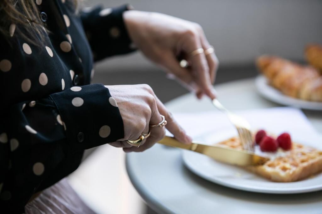 Una persona cortando una rebanada de tostada con un cuchillo.