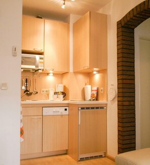 Eine kleine Küche mit Holzausstattung, einer Mikrowelle, einer Kaffeemaschine und einem Geschirrspüler.