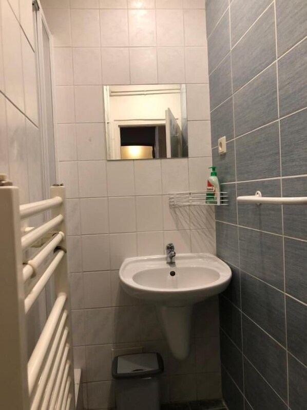 A bathroom with a white sink, a mirror, and a towel rack. - Welcome Hostel & Apartments Praguecentre (Prague)
