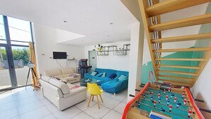 A modern living room with a foosball table, a sofa, a blue couch, and a yellow chair. - Gîte du Fresne, 30min Mt Saint Michel, 15 min Fougères, 13pers+, sauna, jacuzzi (Les Portes du Coglais)