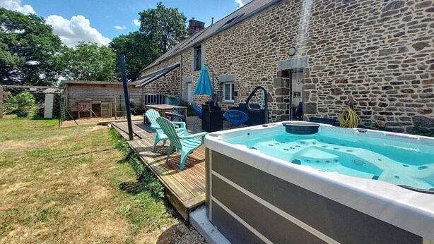 A stone building with a hot tub and outdoor seating. - Gîte du Fresne, 30min Mt Saint Michel, 15 min Fougères, 13pers+, sauna, jacuzzi (Les Portes du Coglais)