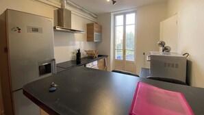 A compact kitchen with a black countertop, stainless steel appliances, and a window providing natural light.