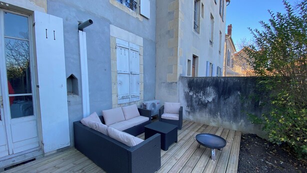 An outdoor patio with a sofa and chairs, a small table, and a grill.