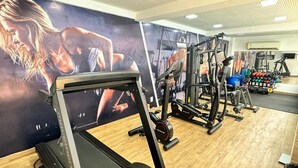 Un gimnasio con equipamiento de ejercicio, suelo de madera y carteles motivacionales en las paredes.