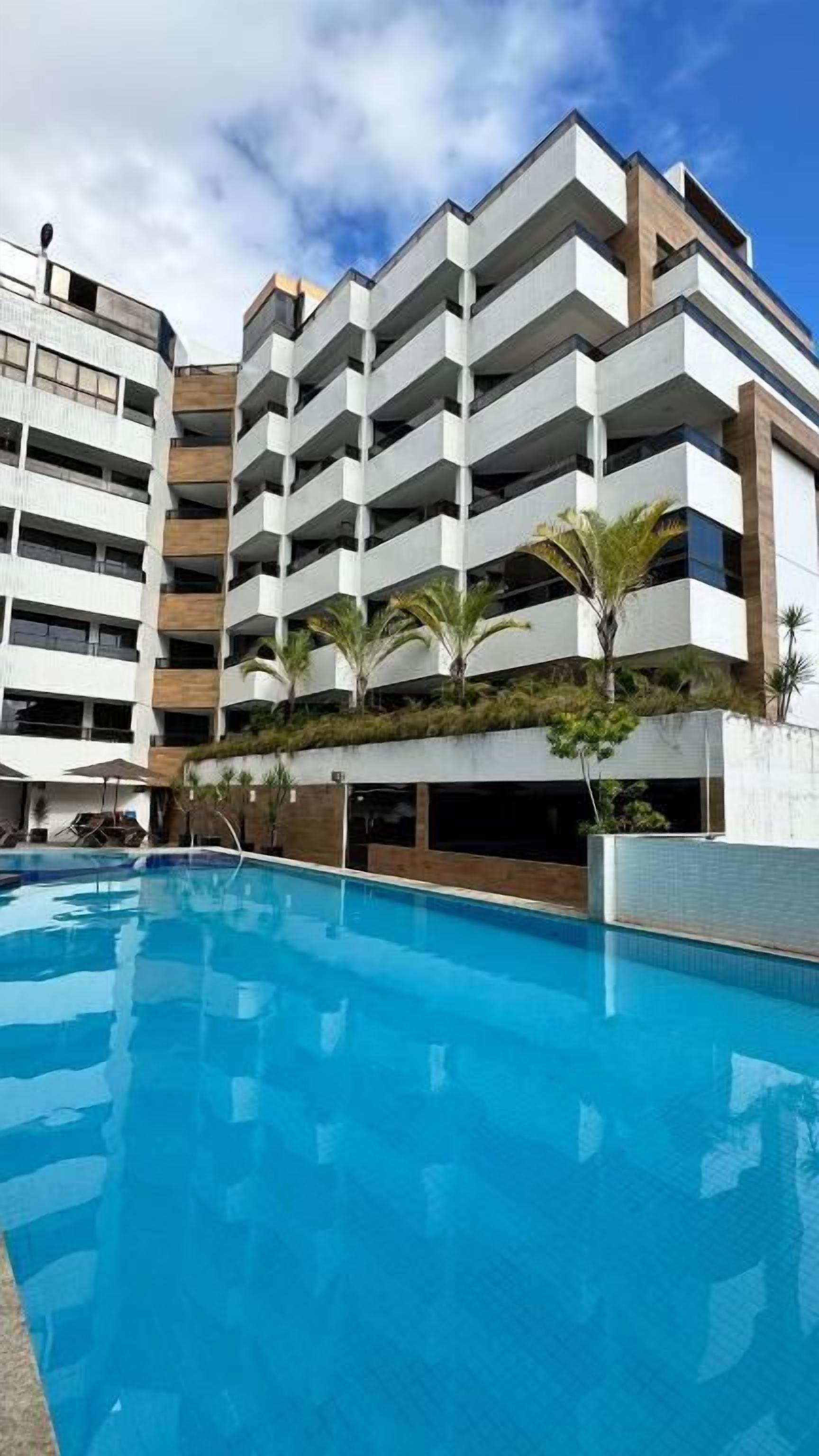 Ein modernes Hotel mit Pool, mehreren Balkonen und blauem Himmel.