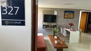 Una habitación de hotel moderna con una cama grande, una pequeña zona de estar, una mesa de comedor, un televisor montado en la pared y un cartel que indica el número de habitación 327.