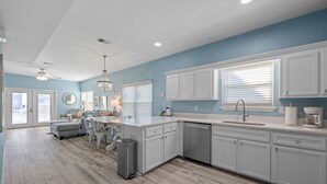 A modern kitchen with white cabinets, a central island, and a dining area with a chandelier. - Private pool - 2nd tier - Entire Duplex (Gulf Shores)