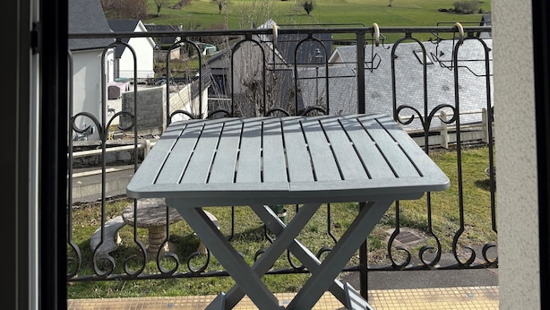 Ein Balkon mit Blick auf ein Gebirge und eine grüne Wiese.