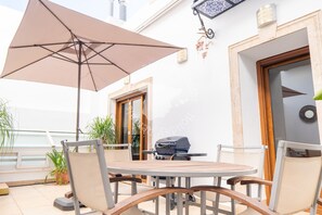An outdoor patio with a round table, chairs, a grill, and a large umbrella. - CostaBlancaDreams - Casa Paquita in Calpe (Calpe)