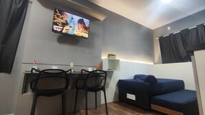 Moderni huone, jossa on seinälle asennettu televisio, sohva ja kaksi tuolia.