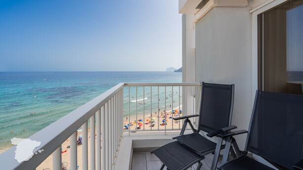 A balcony with two black chairs, overlooking a beach with people and umbrellas. - CostaBlancaDreams - Europa 2 in Calpe (Calpe)
