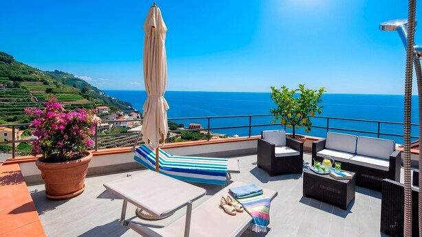 Eine Terrasse mit Lounge-Möbeln, einem Tisch und einem Blumentopf.