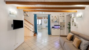 Ein Wohnzimmer mit einer Couch, einem Flachbildfernseher, einer Treppe und einer Küchenzeile mit Pokalen.