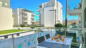 A balcony with a table set for breakfast, overlooking a residential area with modern buildings. - Perla Resort (Ishëm)