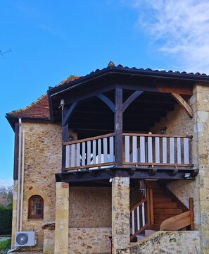 A two-story stone building with a wooden balcony and a staircase leading to the upper floor. - Hameau du jardin Fleuri near Bergerac - 10 gîtes, sleeps 40 (Bosset)