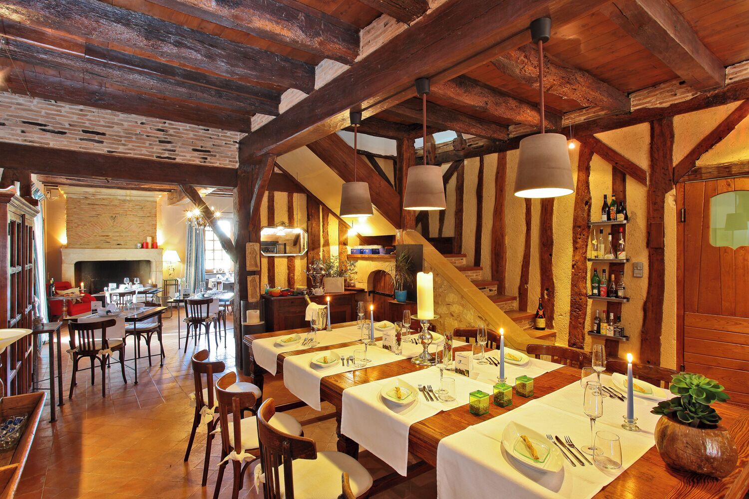 Um restaurante com vigas de madeira, lareira e mesas preparadas para refeições.
